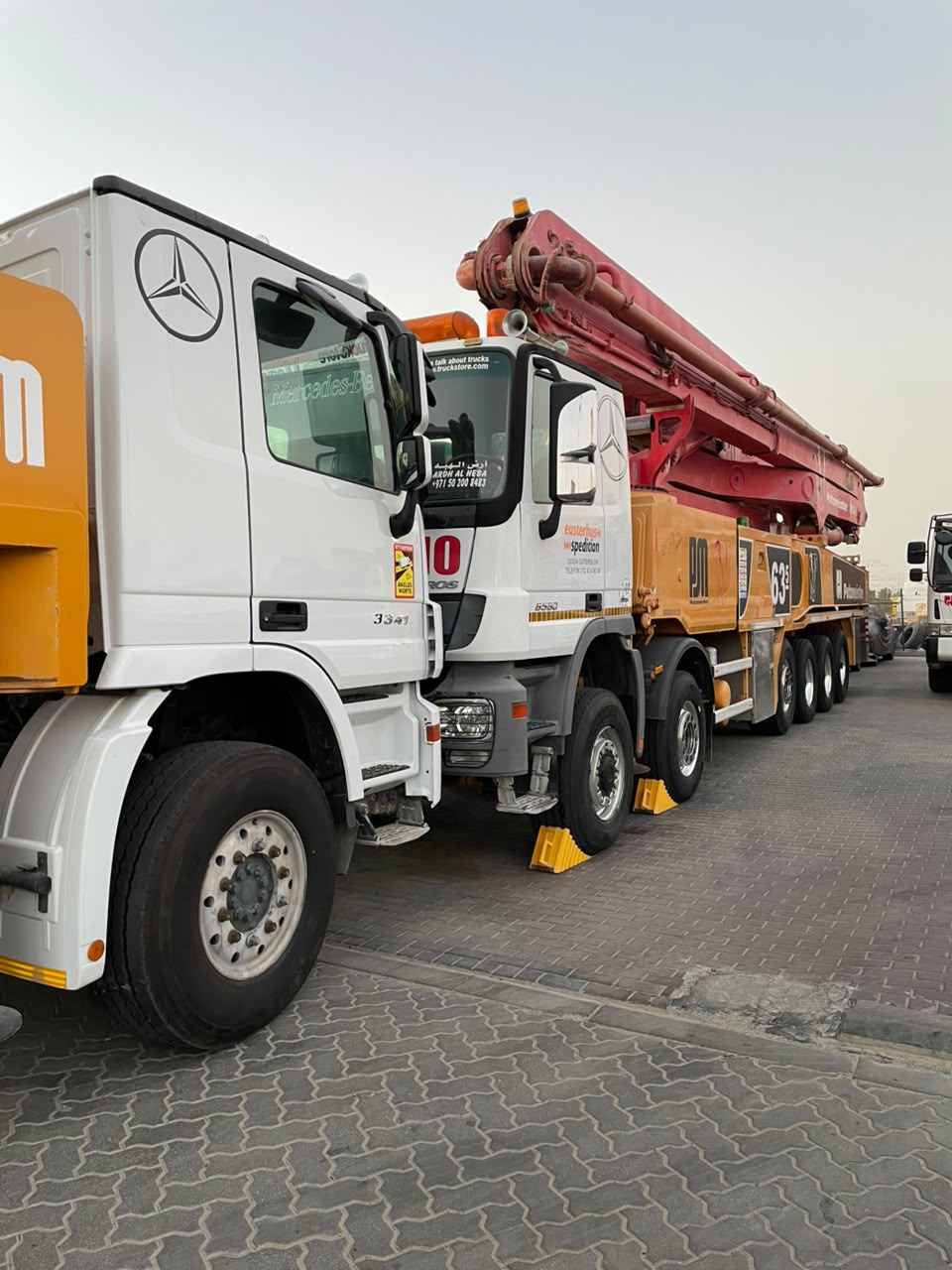 Mercedes-Benz Actros 3341 and 6560 boom pump trucks lined up in the yard